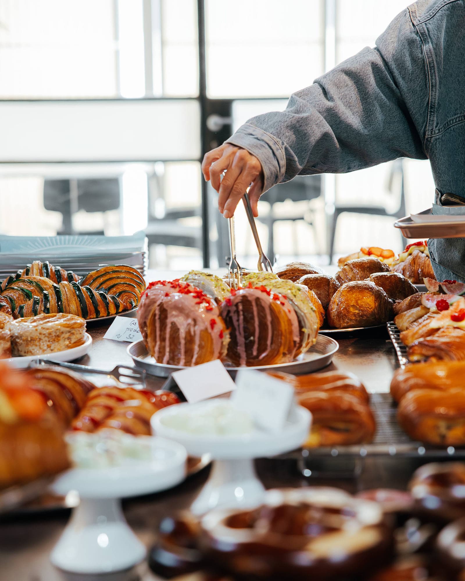 A hand reaching for pastries on a patisserie counter, one of the local stops on the retreat.